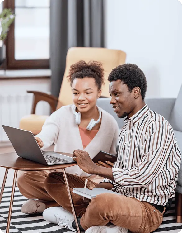 A men and a women sitting oon the carpet and looking at the laptop