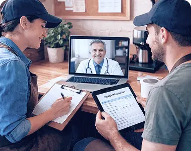 Couple having an online consultation with a doctor via video call while reviewing medical forms at home